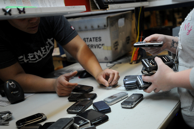 sort cell phones at their work stations at ReCellular's cell phone ...