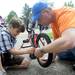 Word of God Community volunteer Pete Hansen, right, shows 6-year-old Ann Arbor resident Izzaldeen Qaraeen how to put the tire back on his bike.  Angela J. Cesere | AnnArbor.com
