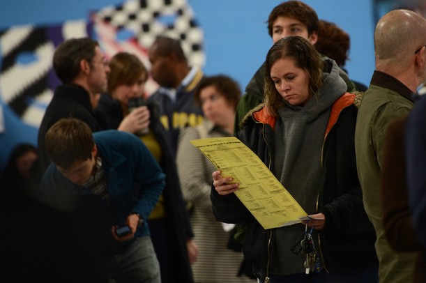 Ann Arbor resident Michelle Clark looks over a sample ballot as she waits in line to vote at Forsythe Middle School on Tuesday morning. Voters were waiting around an hour to cast their vote. Melanie Maxwell I AnnArbor.com