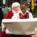 Sitting on Santa's lap, 4-year-old Prince Jerald opens up his gift.
Courtney Sacco I AnnArbor.com  