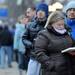 U-M masters student Lisa Spaulding reads a book to pass the time in line on the sidewalk on State Street near the Literature, Science and the Arts Building. Angela J. Cesere | AnnArbor.com
