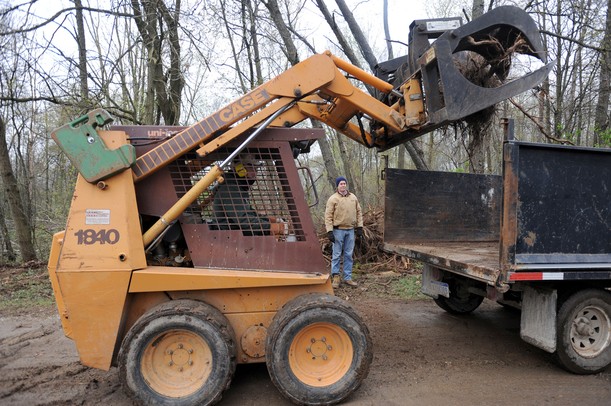 Irish Hills resident Tom Hines, left, moves heavy tree stumps and roots into a flatbed truck on the property of the Fike family. Angela J. Cesere | AnnArbor.com