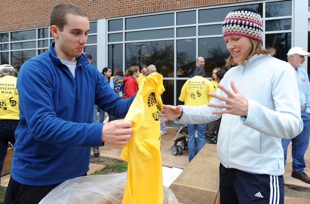 Volunteer David Goldberg, left, hands a Dexter Wellness Walk shirt to Dexter resident Julie Newton outside of Dexter District Library on Saturday morning. The walk, which started as a way to keep people fit, changed into an event to raise money for the Dexter Relief Fund, set up to help victims of the tornado recover. Angela J. Cesere | AnnArbor.com