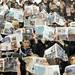 The Dexter student section holds up newspapers to look at while the Chelsea boys basketball team starters are announced. Angela J. Cesere