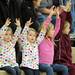 From left: Dexter residents Ava and Vanessa Rodriguez, age 4, their sister Branna, age 7, and friend Maddie Valentine, age 8, hold their hands up to cheer on a Dexter free-throw. Angela J. Cesere