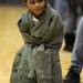 2-year-old Ypsilanti resident Kaiden Guidly stands next to the bleachers with an adult size coat on. Kaiden's sister NyRee Watson plays for Ypsilanti. Angela J. Cesere